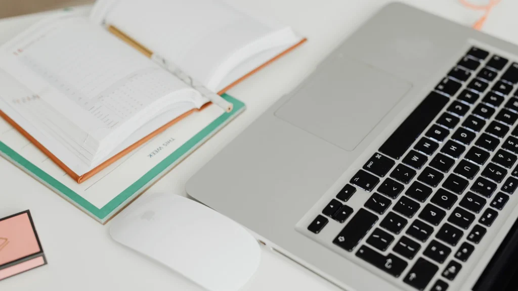laptop, desk calendar and notebook arranged for appointment planning