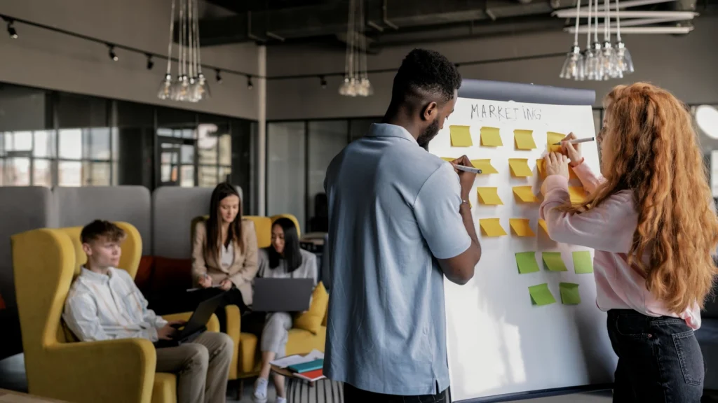 two colleagues mapping a customer workflow with sticky notes on a whiteboard