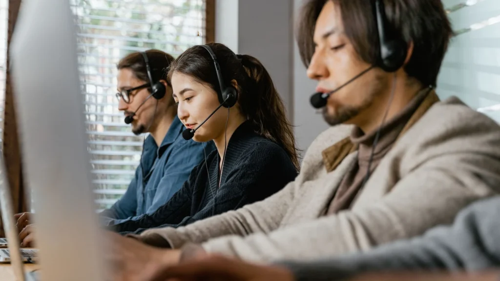 customer support team working with headsets and laptops in an office