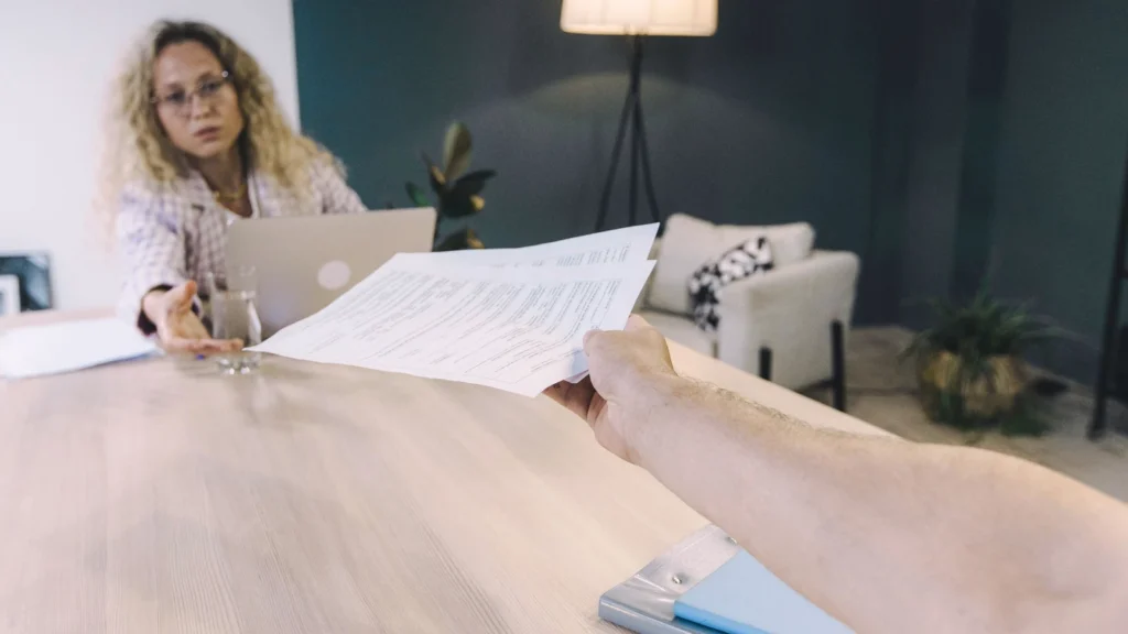 colleagues exchanging a printed website project brief in an office